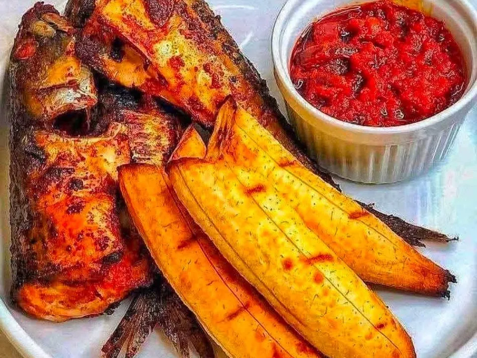 Grilled fish with fried plantain and a pot of pepper sauce