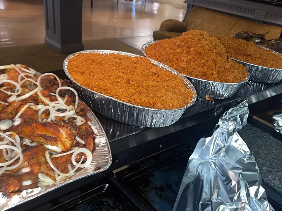 Foil trays of jollof rice and chicken laid out for a party