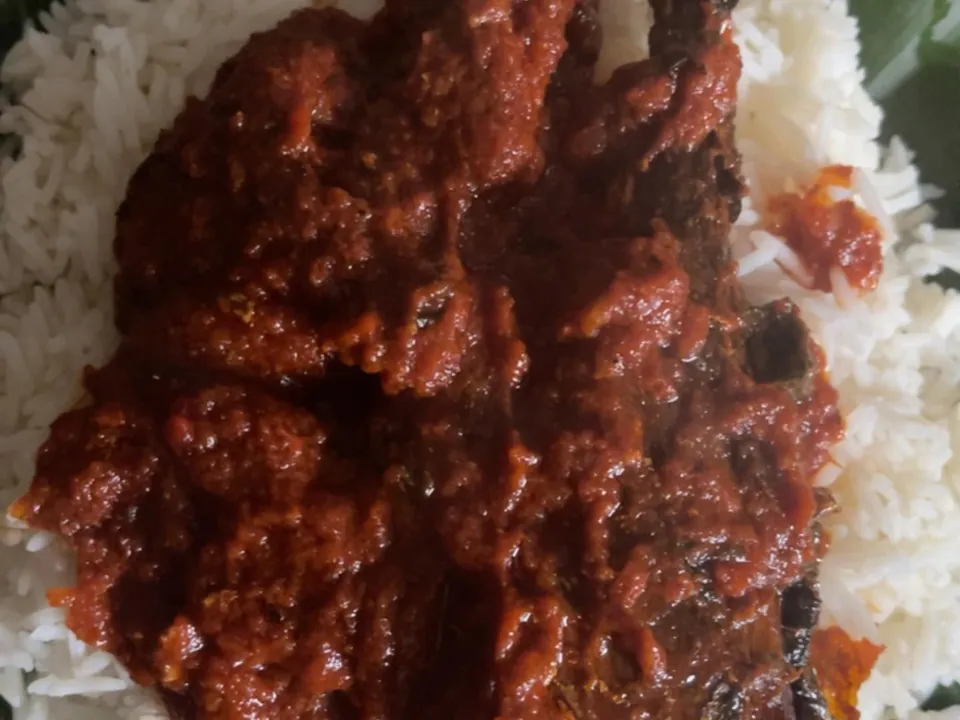 White rice with a red stew on a leaf