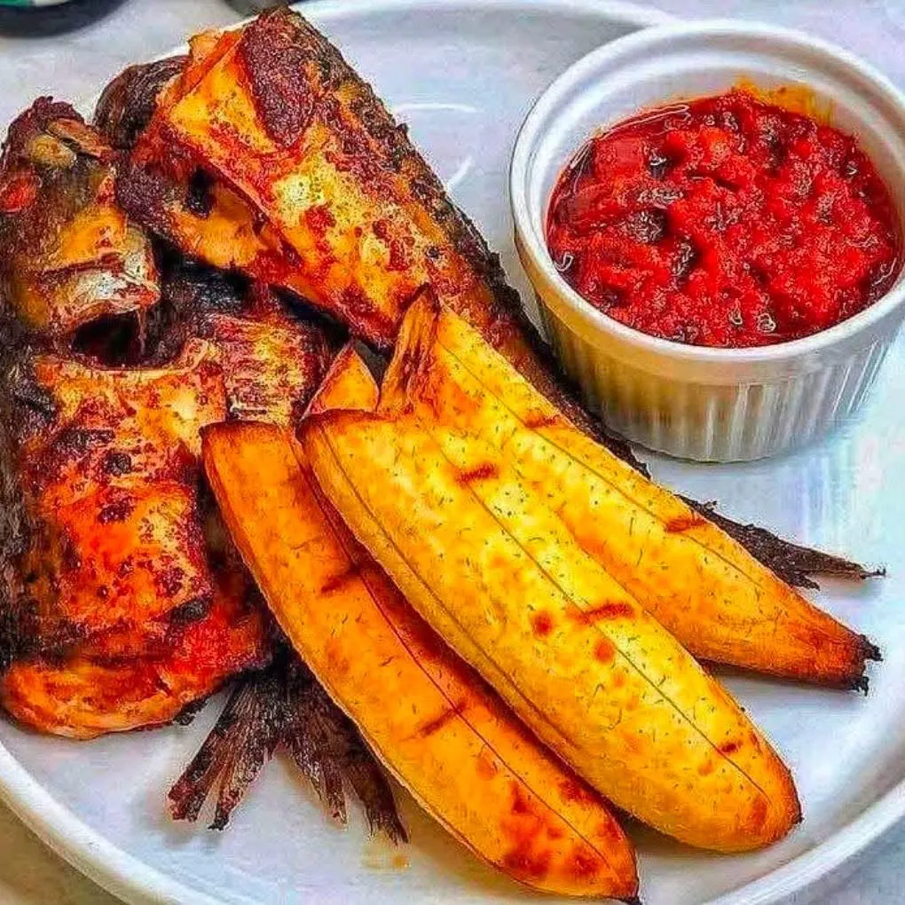 Grilled fish with fried plantain and a pot of pepper sauce
