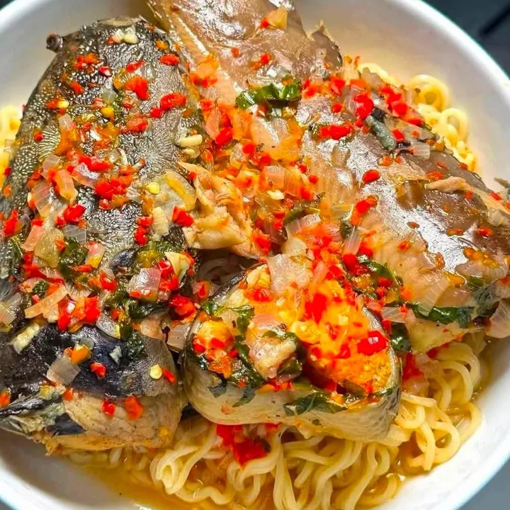 Fish in a fresh pepper and onion sauce over noodles, in a bowl