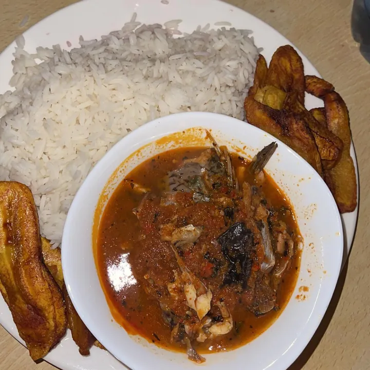 White rice, a bowl of fish soup and fried plantain on one plate