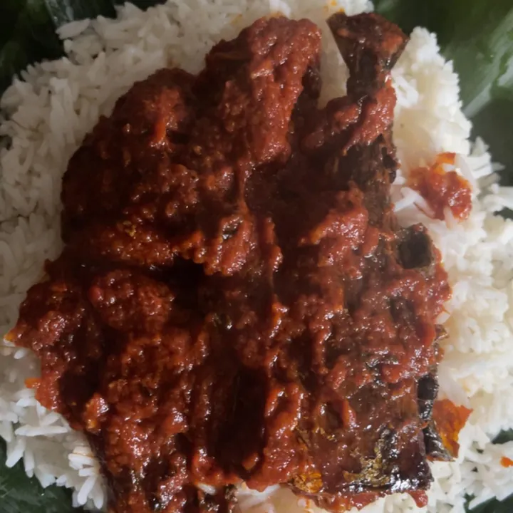 White rice with a red stew on a leaf