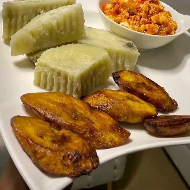 Boiled yam, egg sauce and fried plantain on a white plate